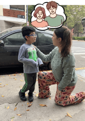Niño pidiéndole ayuda a una adulta que se agacha a su altura.
