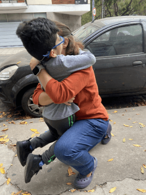 Niño abrazando emocionado a su mamá en la calle.